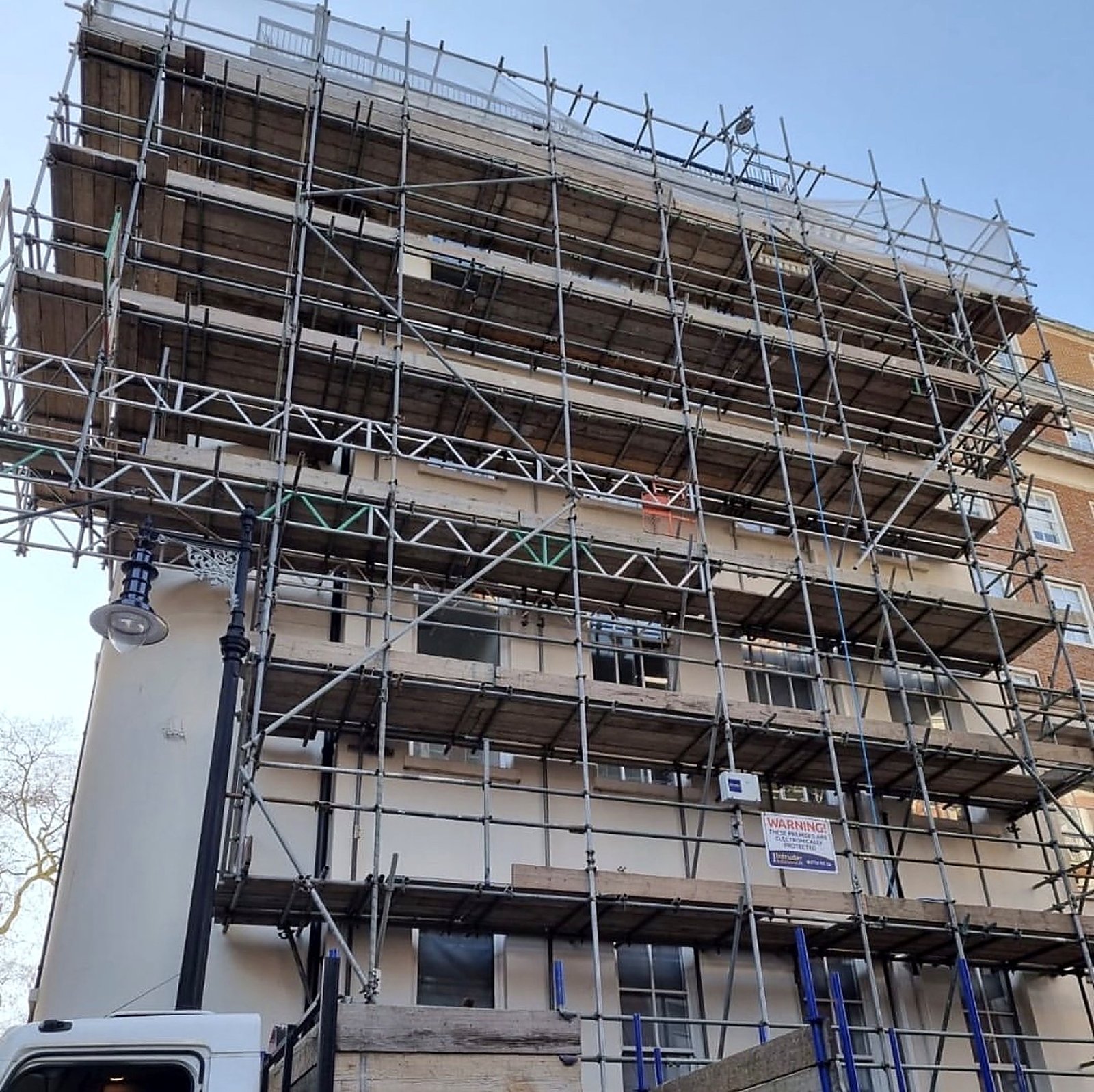 Tall scaffold with a cantilevered lift on a stucco facade