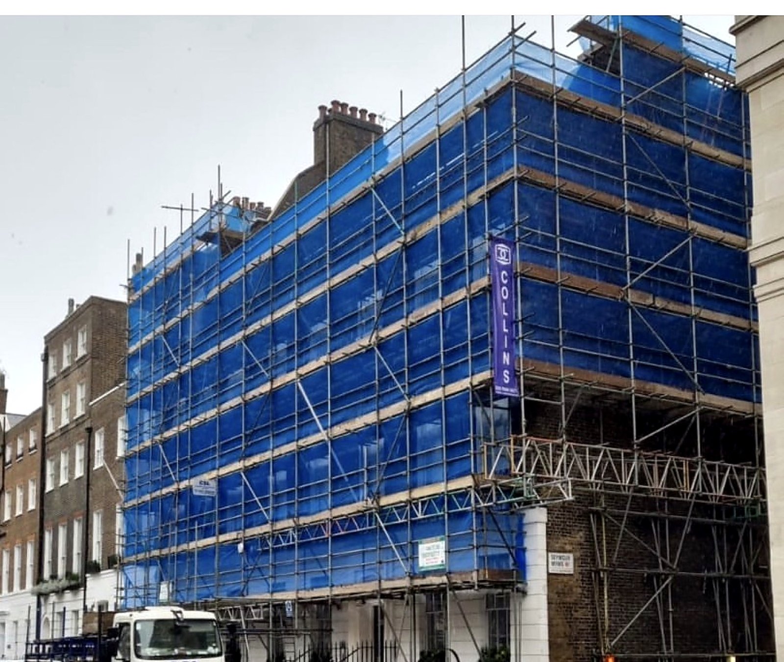 Blue-sheeted scaffold wrapping the corner of a London terrace