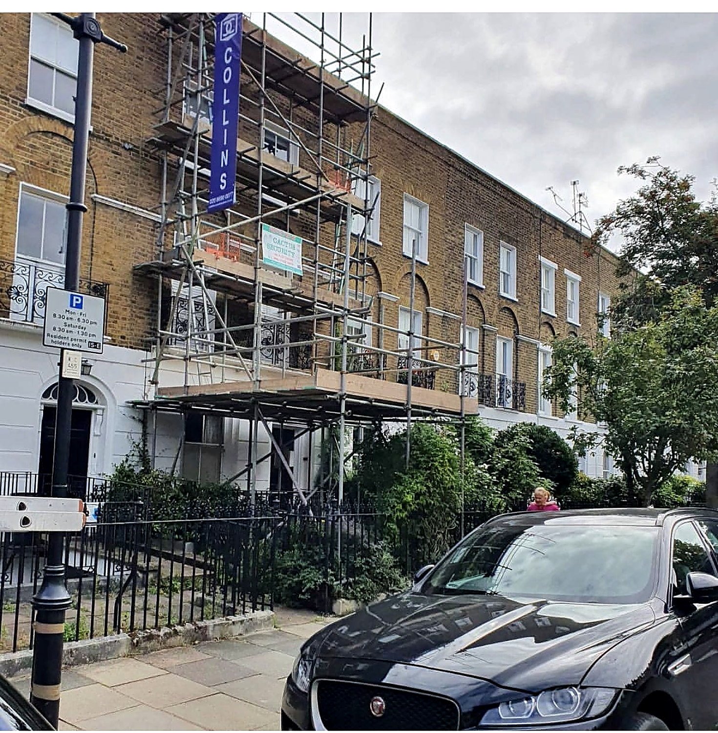 Scaffold on a period terrace beside a tree-lined London street